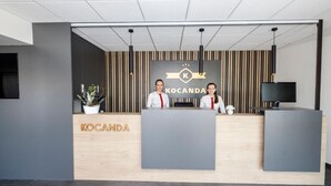 Un comptoir d’accueil avec deux employés, un logo et un téléviseur.