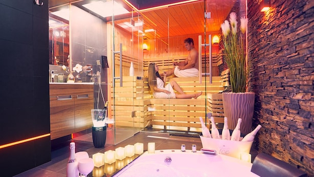 Un sauna avec des bancs en bois, une paroi en verre et une grande plante en pot.
