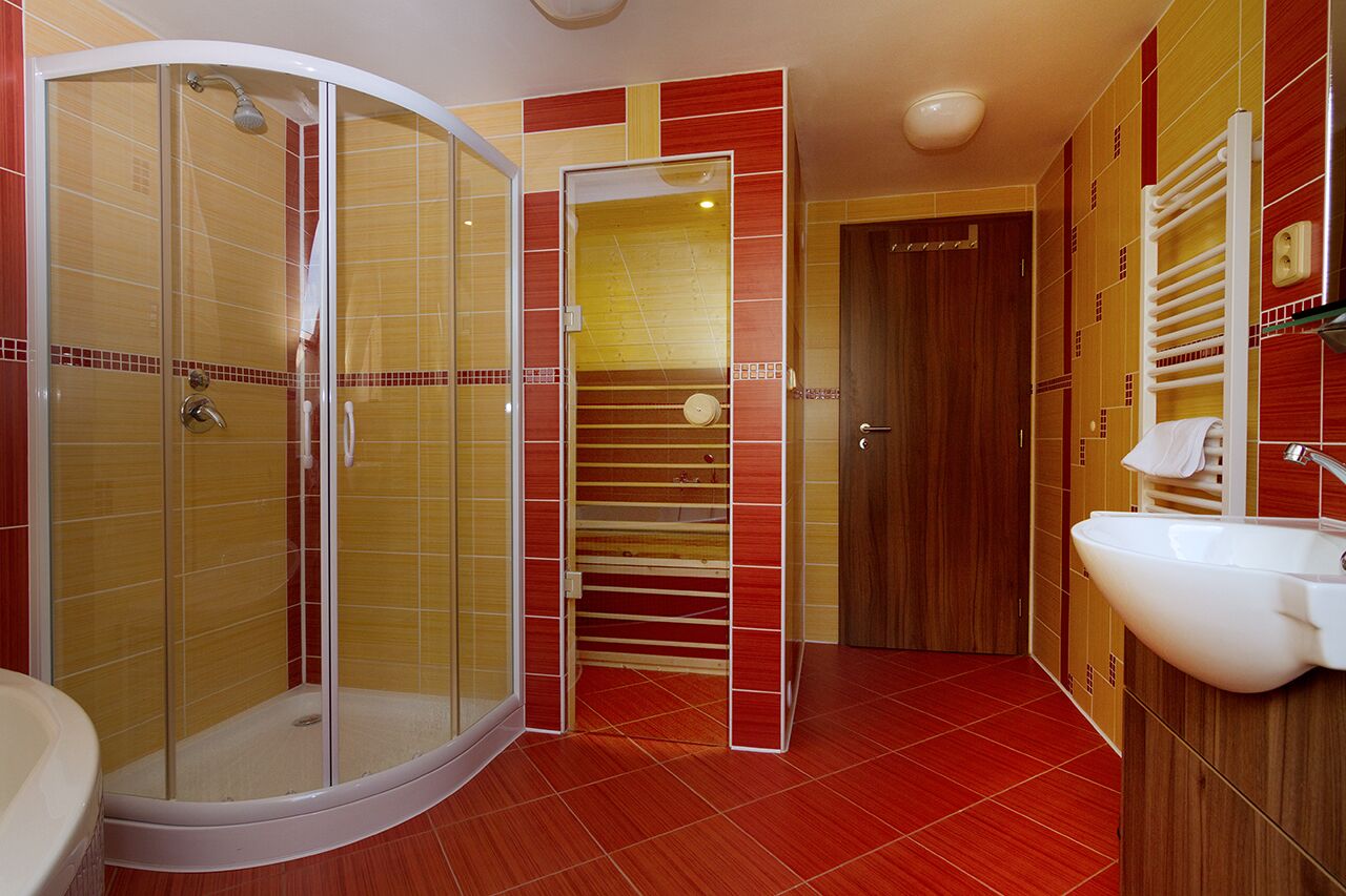 Une salle de bain avec une douche à parois de verre, un lavabo blanc et une porte en bois.