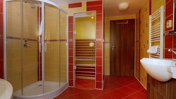 Une salle de bain avec une douche à parois de verre, un lavabo blanc et une porte en bois.