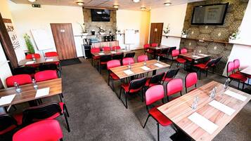 A conference room with multiple tables and chairs, equipped with water bottles and notepads.