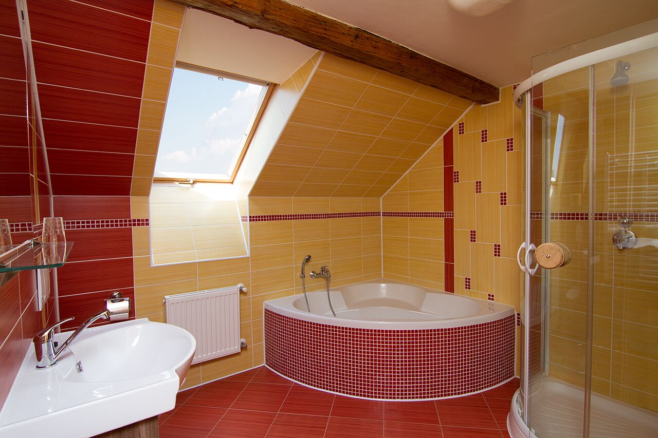 A bathroom with a skylight, a bathtub, a shower, and a sink.