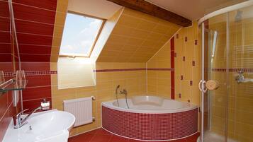 A bathroom with a skylight, a bathtub, a shower, and a sink.