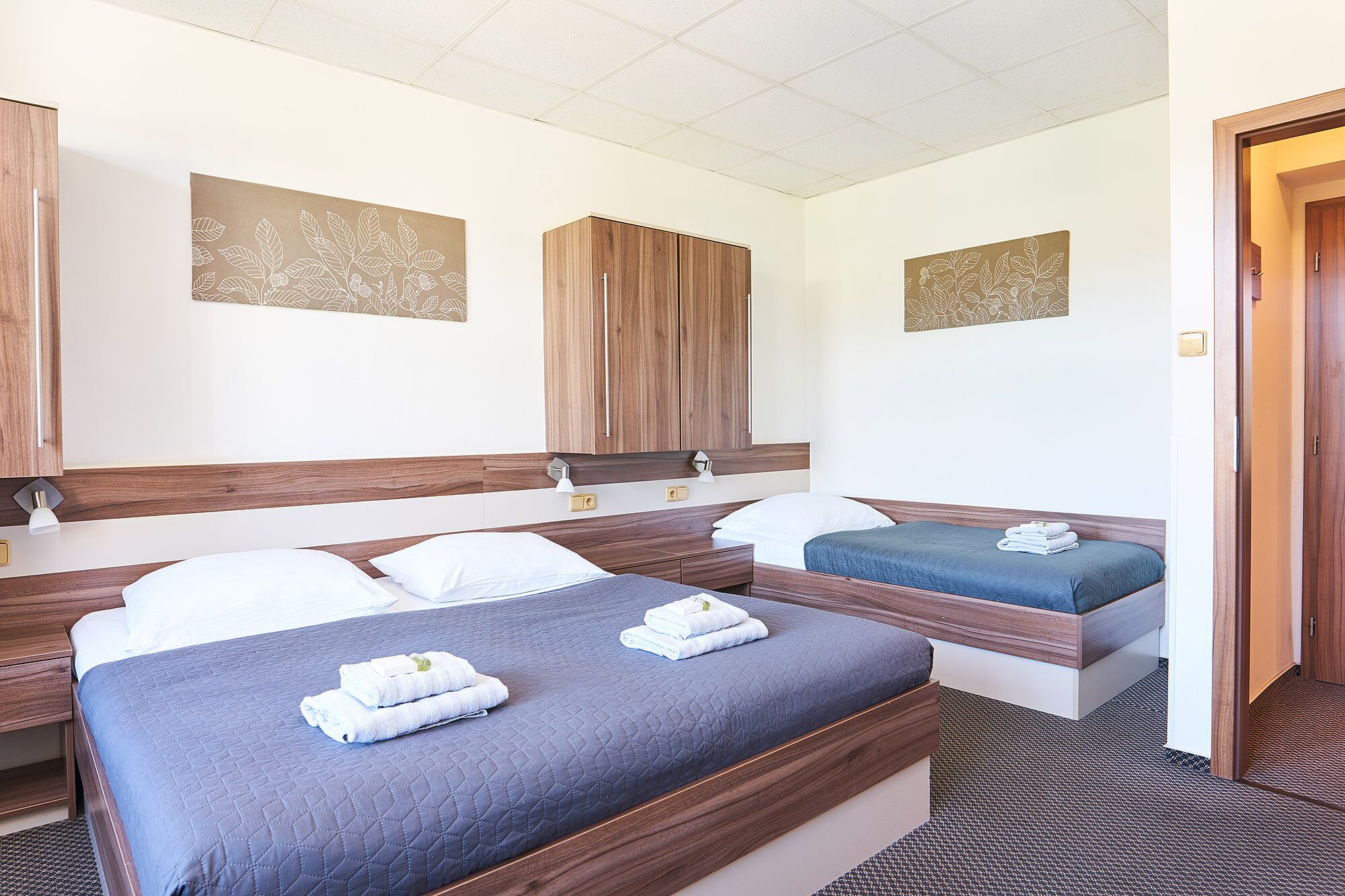 A hotel room with two beds, a wooden headboard, and a large mirror.