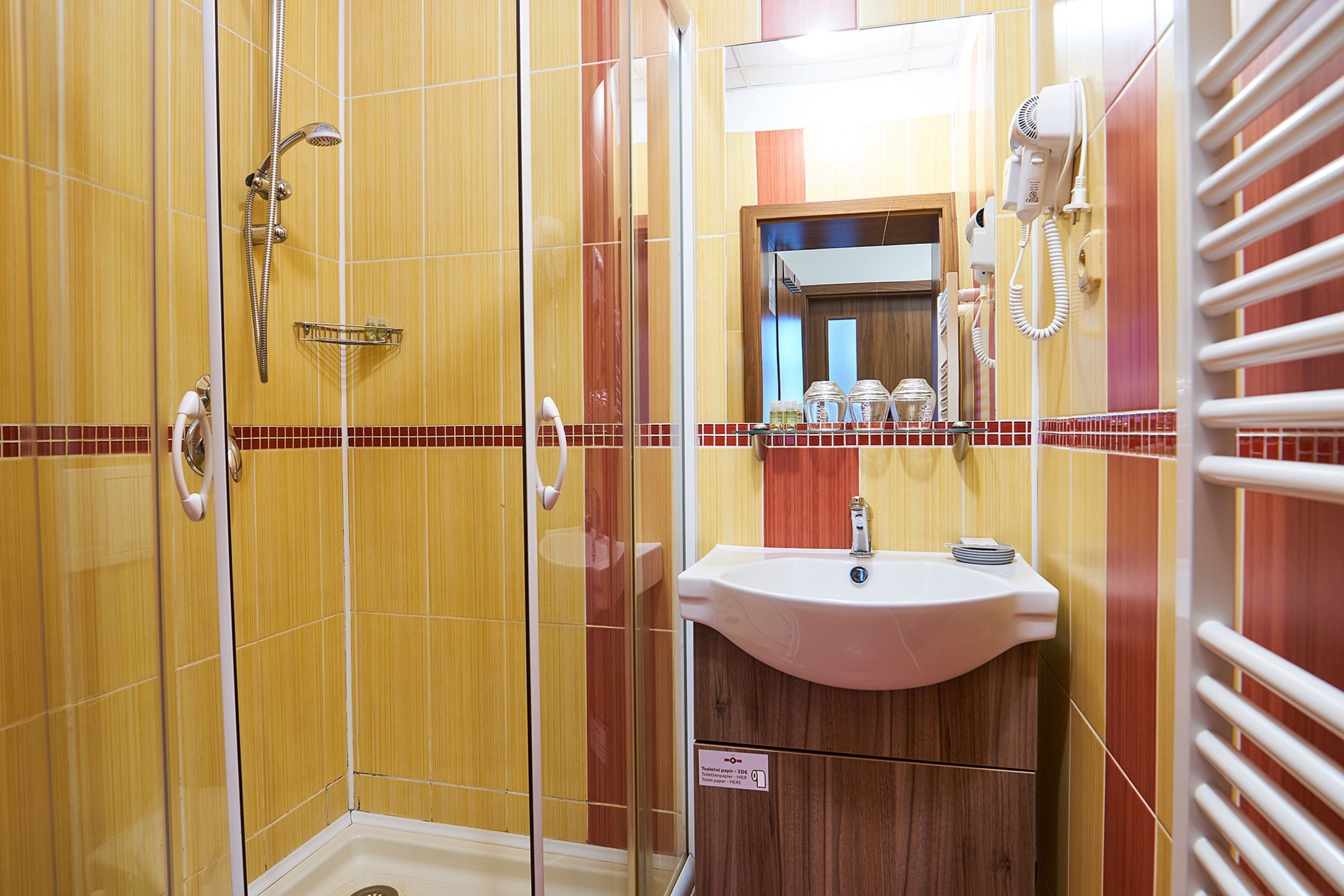 A bathroom with a glass-enclosed shower, a sink with a mirror above it, and a towel rack.