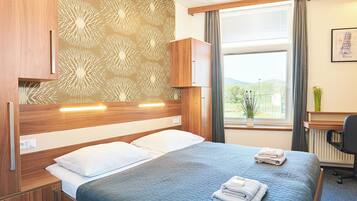 Habitación de hotel con cama, escritorio y ventana con vistas a zonas verdes.