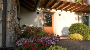 Un bâtiment en pierre avec une porte en bois, des plantes en pot et un chemin pavé de briques.