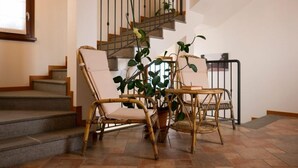Un escalier avec une rampe en métal, une chaise en osier, une plante en pot et une table en osier avec des chaises.