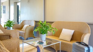 Une chambre d’hôtel moderne avec un canapé en osier, une table basse en verre et une plante en pot.