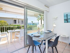 Ein Balkon mit einem Glastisch, Stühlen und einer Weinflasche.