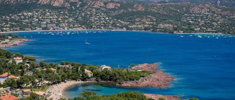 A coastal town with a marina, rocky coastline, and mountainous backdrop.