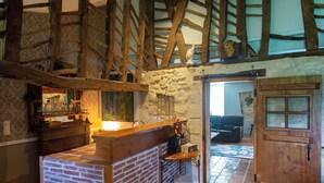 A rustic kitchen with exposed beams, a stone wall, and a wooden counter. - Le Domaine d'Ardgalen (Val de Virvée)