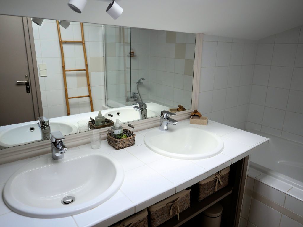 A bathroom with two sinks, a large mirror, and a bathtub.