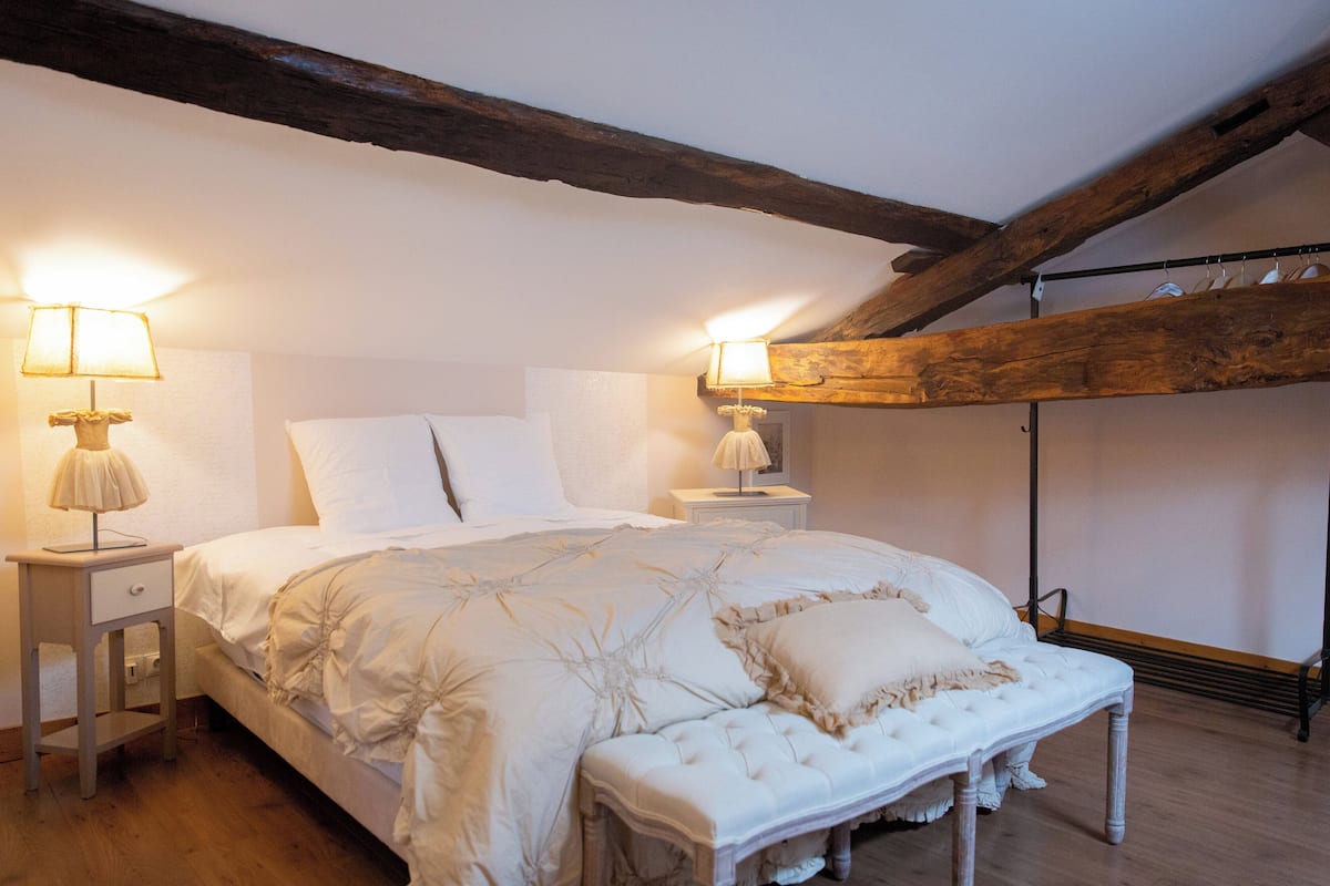 Een slaapkamer met een groot bed, twee nachtkastjes en een houten plafondbalk.