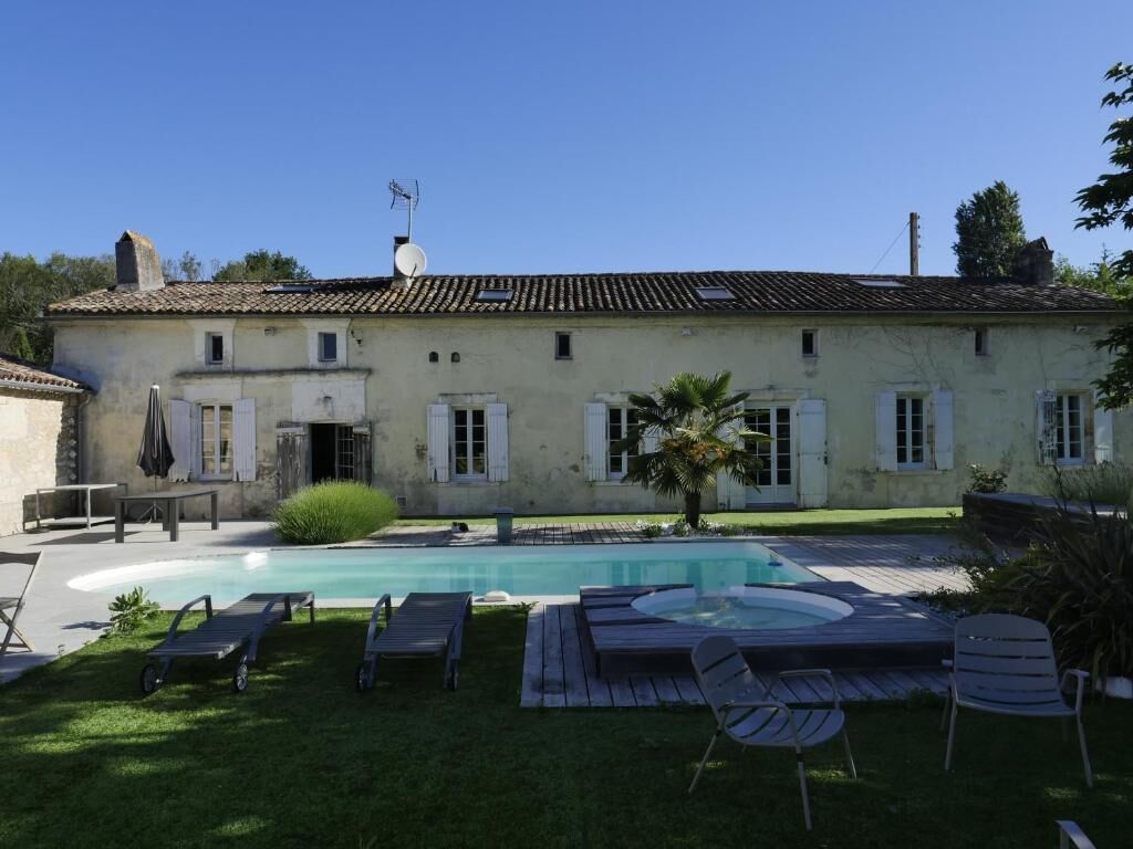 A building with a swimming pool, outdoor seating, and a well-maintained lawn.
