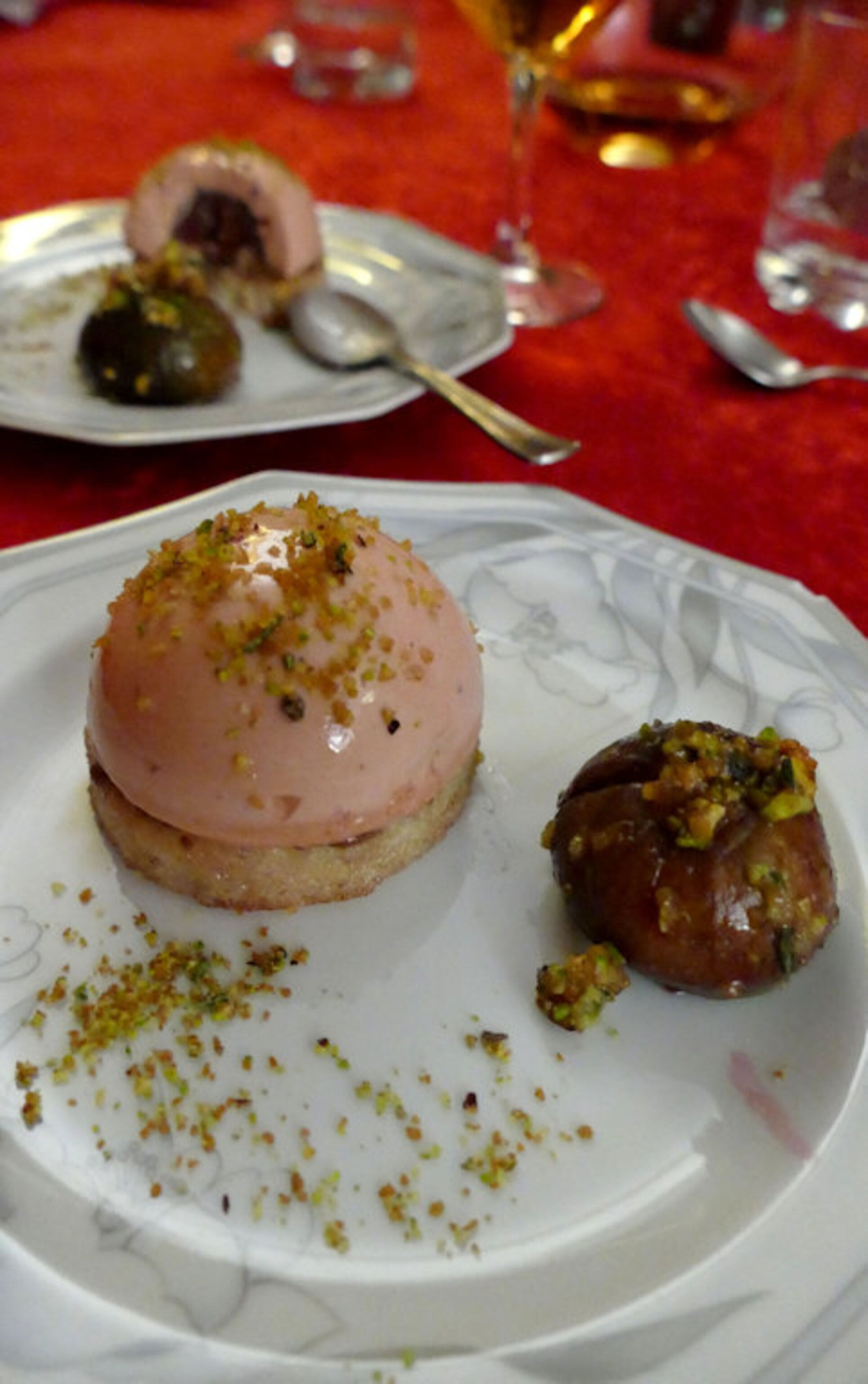 Un plato con un postre en forma de cúpula rosa y un pastel redondo sobre una fuente blanca.