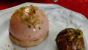Un plato con un postre en forma de cúpula rosa y un pastel redondo sobre una fuente blanca.