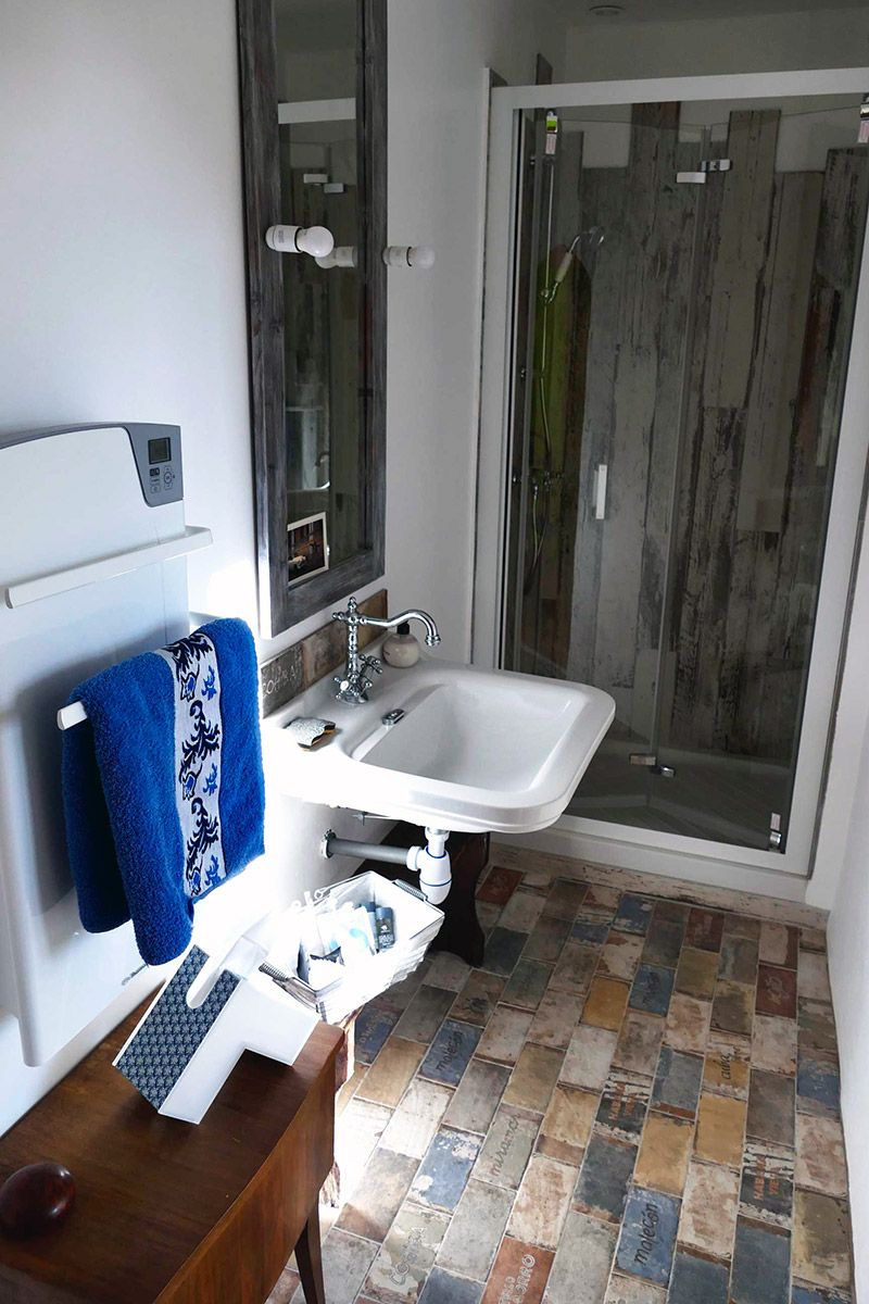 A bathroom with a white sink, a mirror, a blue towel, and a shower area.