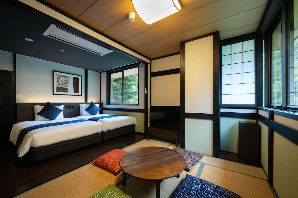 Une chambre d’hôtel avec un lit, une petite table et une fenêtre donnant sur un paysage verdoyant.