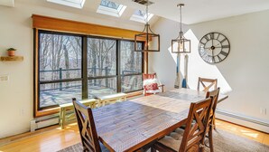 Een eetgedeelte met een groot raam, een houten tafel en stoelen.
