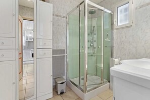 A modern bathroom with a glass-enclosed shower, a white sink, and a toilet.
