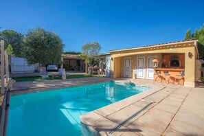 A swimming pool with a bar area, outdoor seating, and a stone building with a tiled roof. - Homerez - Holiday Apartment in Vidauban (Vidauban)