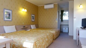 Una habitación de hotel con dos camas, un escritorio, un televisor y un equipo de aire acondicionado.