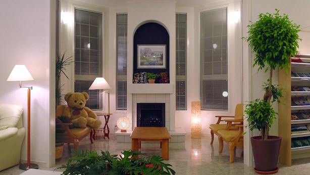 Un salón con chimenea, un gran osito de peluche y una planta en maceta.