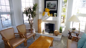 Una sala de estar con chimenea, dos sillones, una mesa de centro y un sofá.