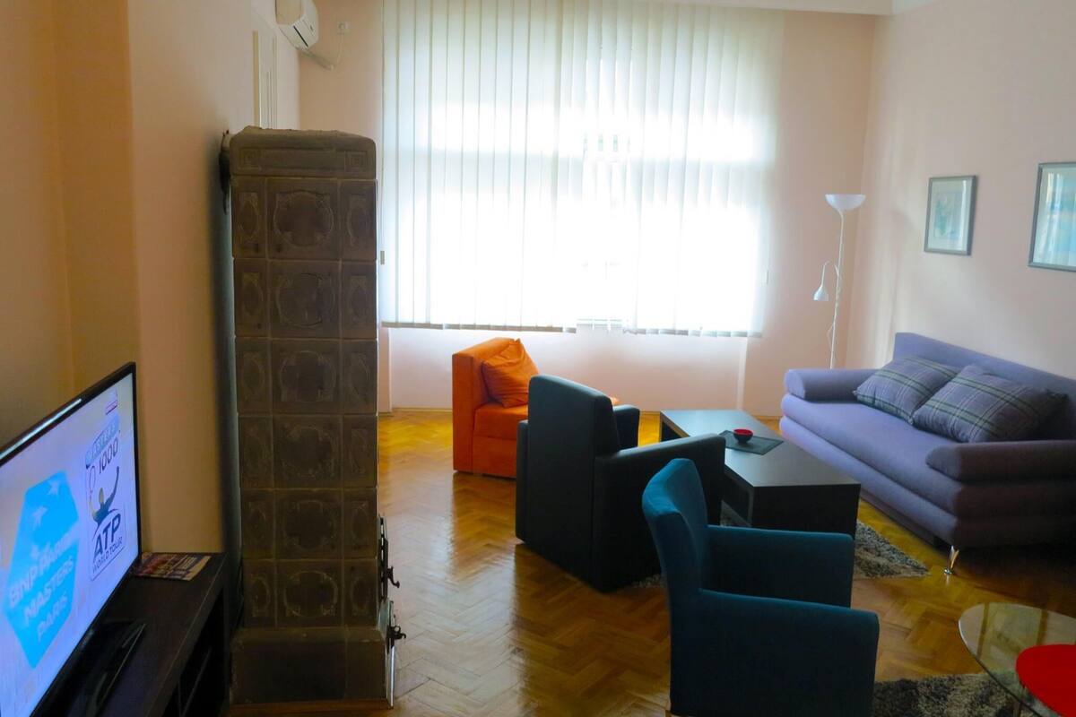 Una sala de estar con sofá, sillones, una mesa de centro y televisor.