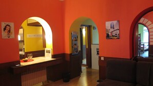 A hotel lobby with orange walls, a reception desk, and a seating area. - Traveler's Hostel & Apartments (Belgrade)
