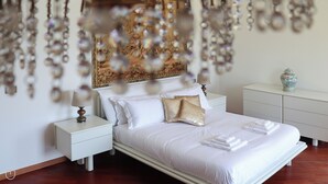 A neatly made bed with white linens and a gold accent pillow, a bedside table with a lamp, and a decorative vase on a dresser. - Italianway - San Bartolomeo 7 (Rapallo)