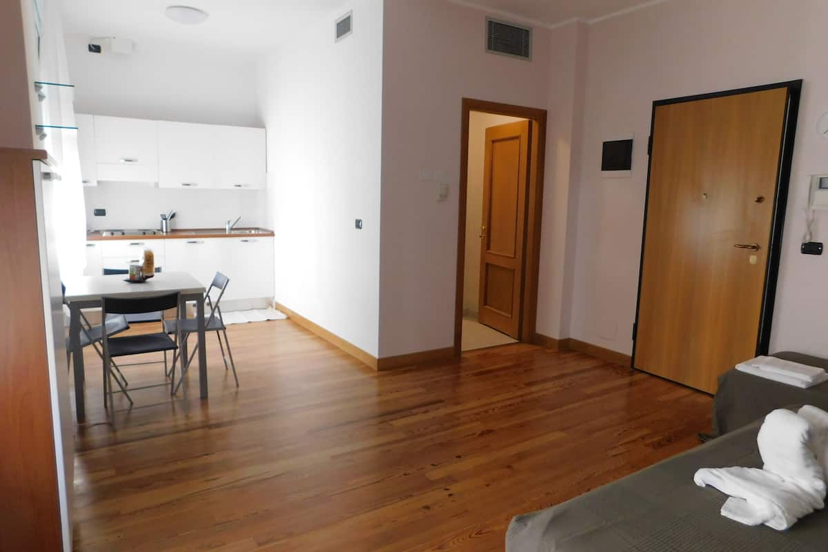 Un espace de vie compact comprenant un coin cuisine, un coin repas et une chambre.