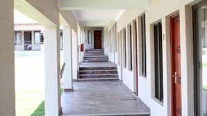 Ein überdachter Gang mit Fliesenboden, der zu einer Treppe und mehreren Türen führt.