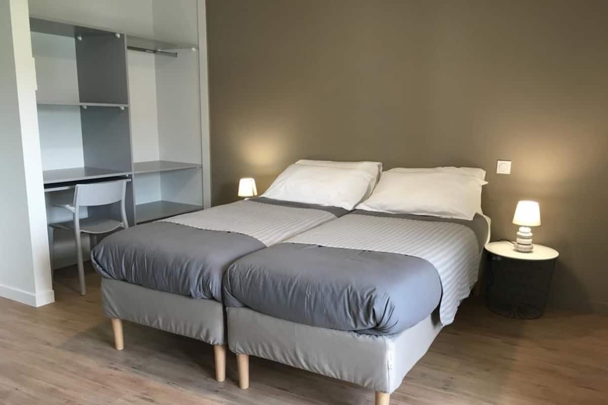 A bedroom with a bed, bedside tables, a desk, and a wardrobe.