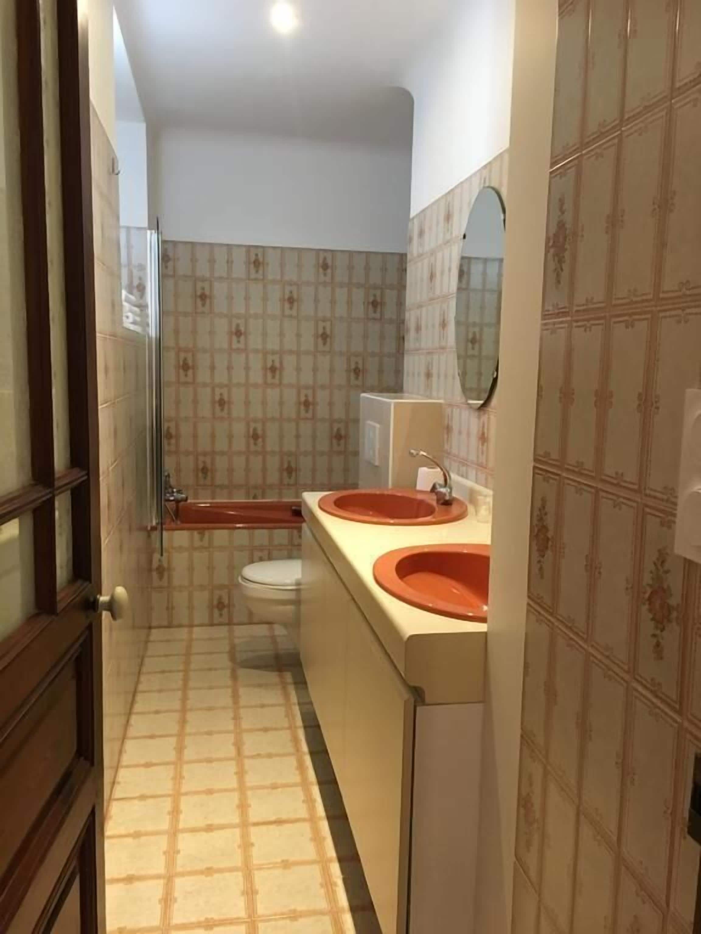 Et badeværelse med to håndvaske, toilet og bruser.