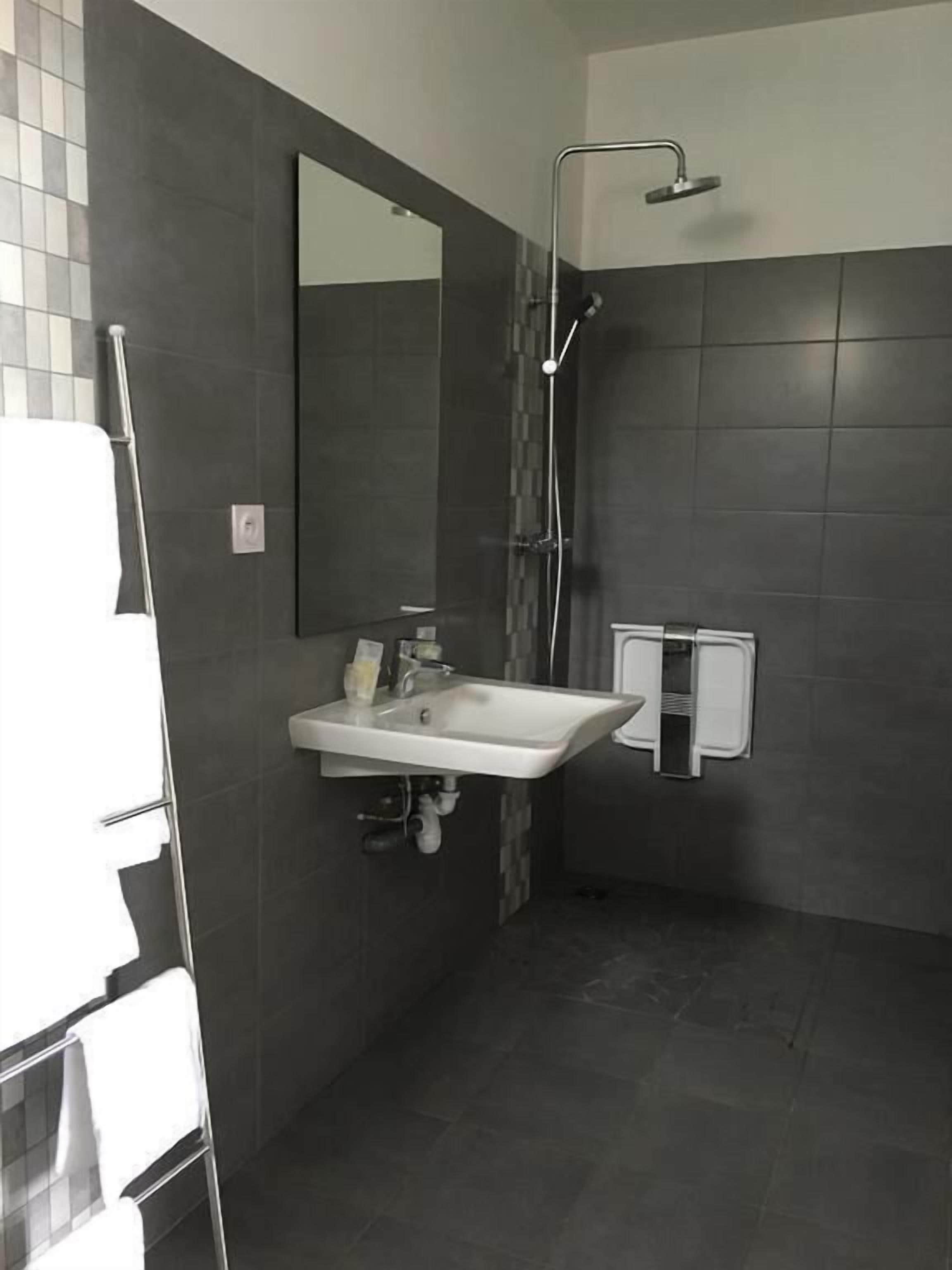 Een moderne badkamer met een witte wastafel, een spiegel en een douche.