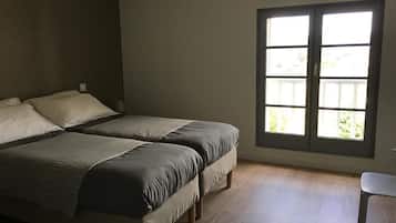Une chambre avec deux lits, une fenêtre donnant sur un beau paysage et un fauteuil.