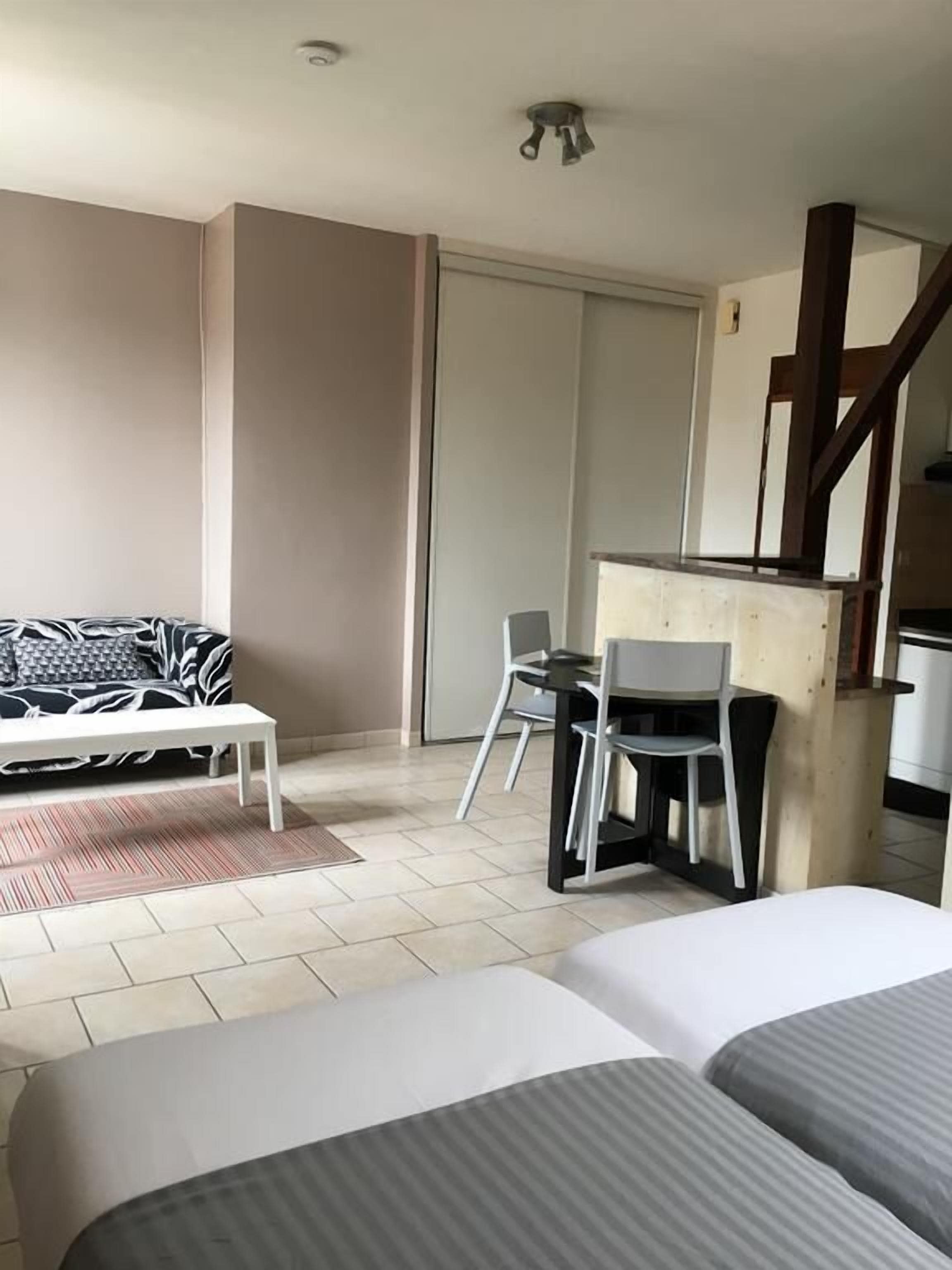 A hotel room with a bed, a sofa, a dining table with chairs, and a kitchenette.