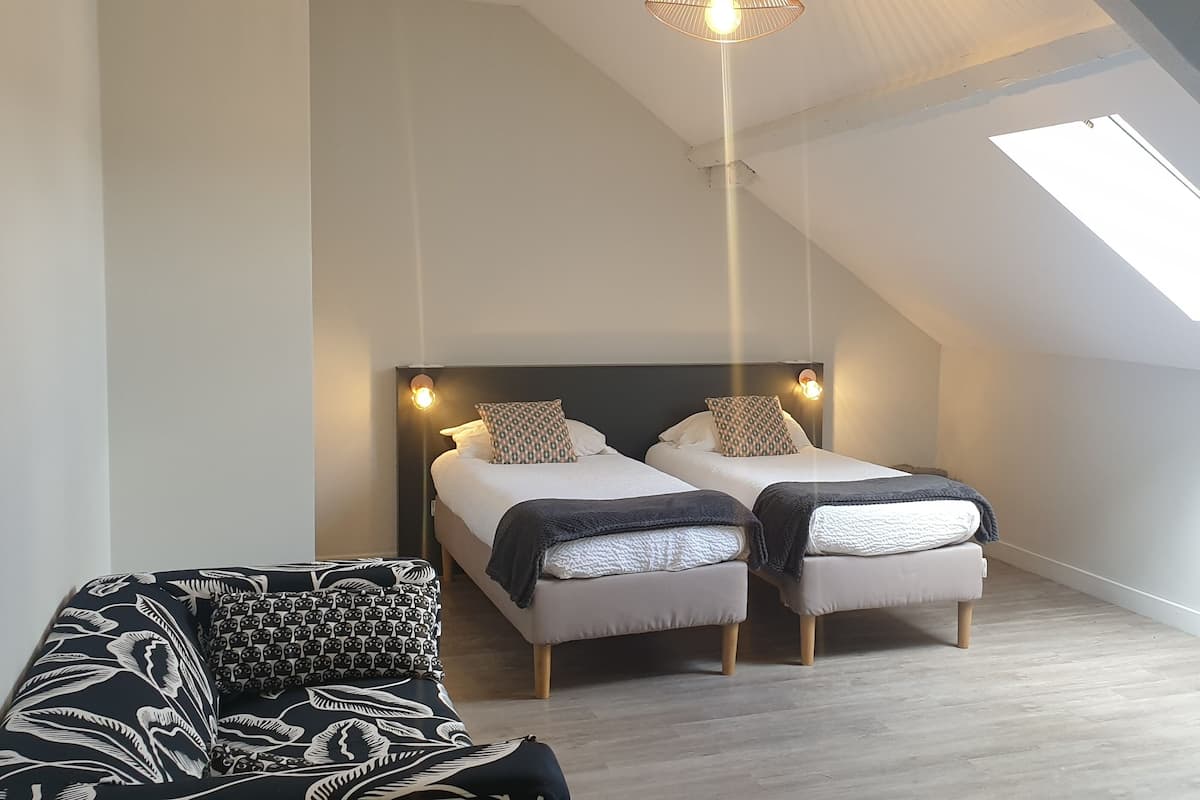 A compact bedroom with two beds, a TV on a stand, and a skylight.