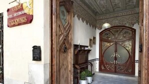 La entrada de un hotel con una puerta de madera grande, un letrero y suelo de baldosas.
