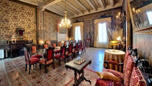 Una sala imponente con techo ricamente decorado, paredes con diseños y una lámpara de cristal.