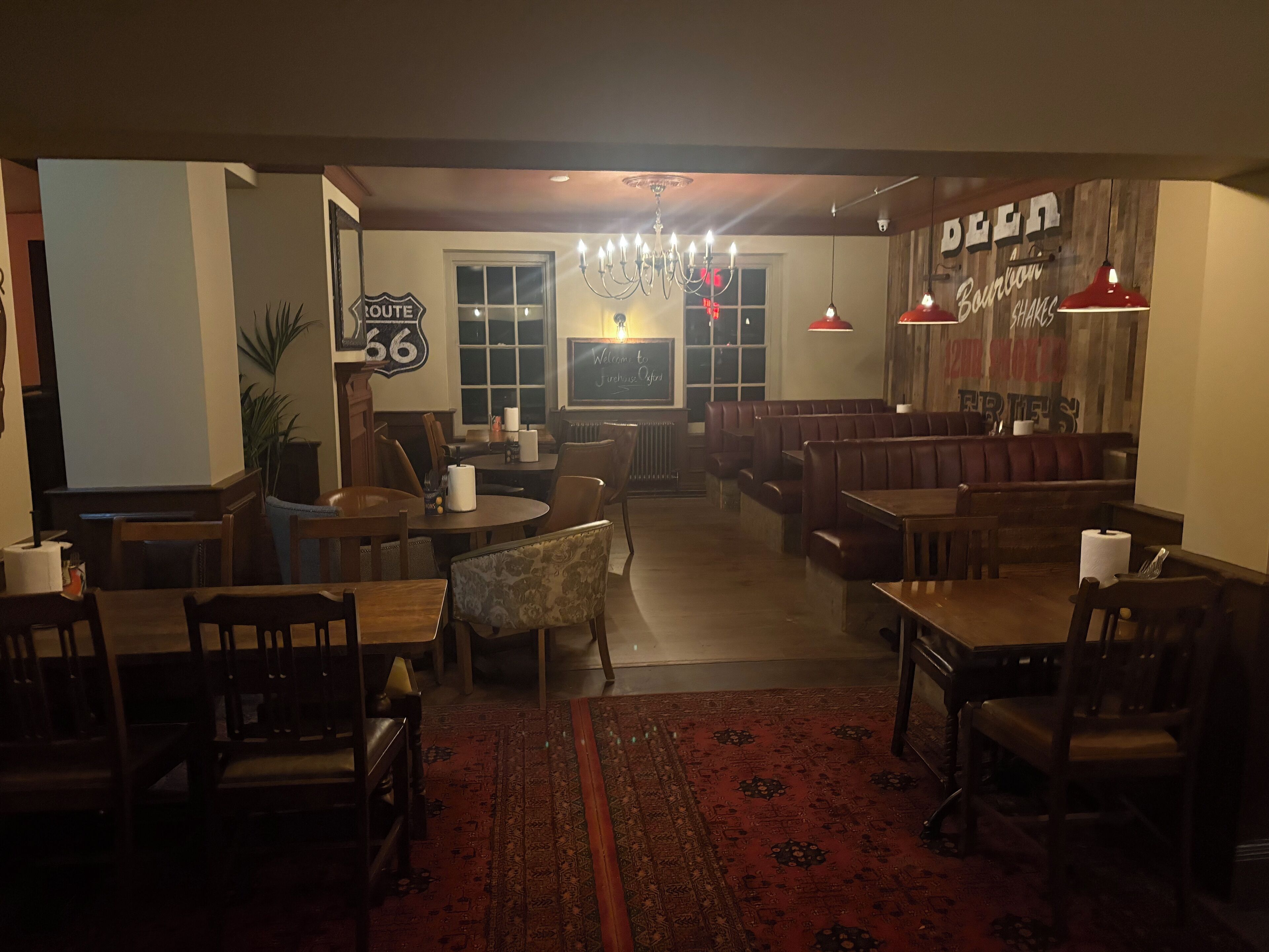 Un restaurante acogedor con cabinas y mesas, un letrero antiguo y un candelabro.