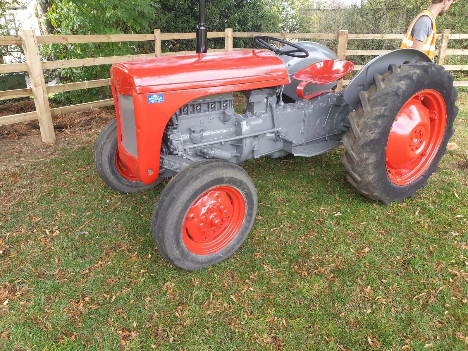 Een rode tractor met grote zwarte banden geparkeerd op gras.