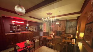 A restaurant interior with wooden tables and chairs, a bar area, and a fireplace. - The Evenlode Rooms at Firehouse Oxford (Witney)