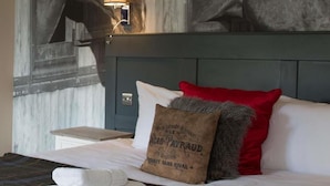 A neatly made bed with white linens, a plaid blanket, and a red pillow. - The Evenlode Rooms at Firehouse Oxford (Witney)