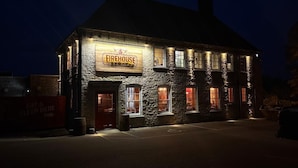 A stone building with a sign reading "Firehouse BBQ & Bar" and a red door. - The Evenlode Rooms at Firehouse Oxford (Witney)
