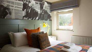 A hotel room with a bed, pillows, a blanket, a window with a view, and a wall-mounted lamp.