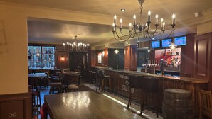 A bar area with wooden tables and chairs, a bar counter with a sign reading "SMOKY BO COLD BEER", and a chandelier. - The Evenlode Rooms at Firehouse Oxford (Witney)
