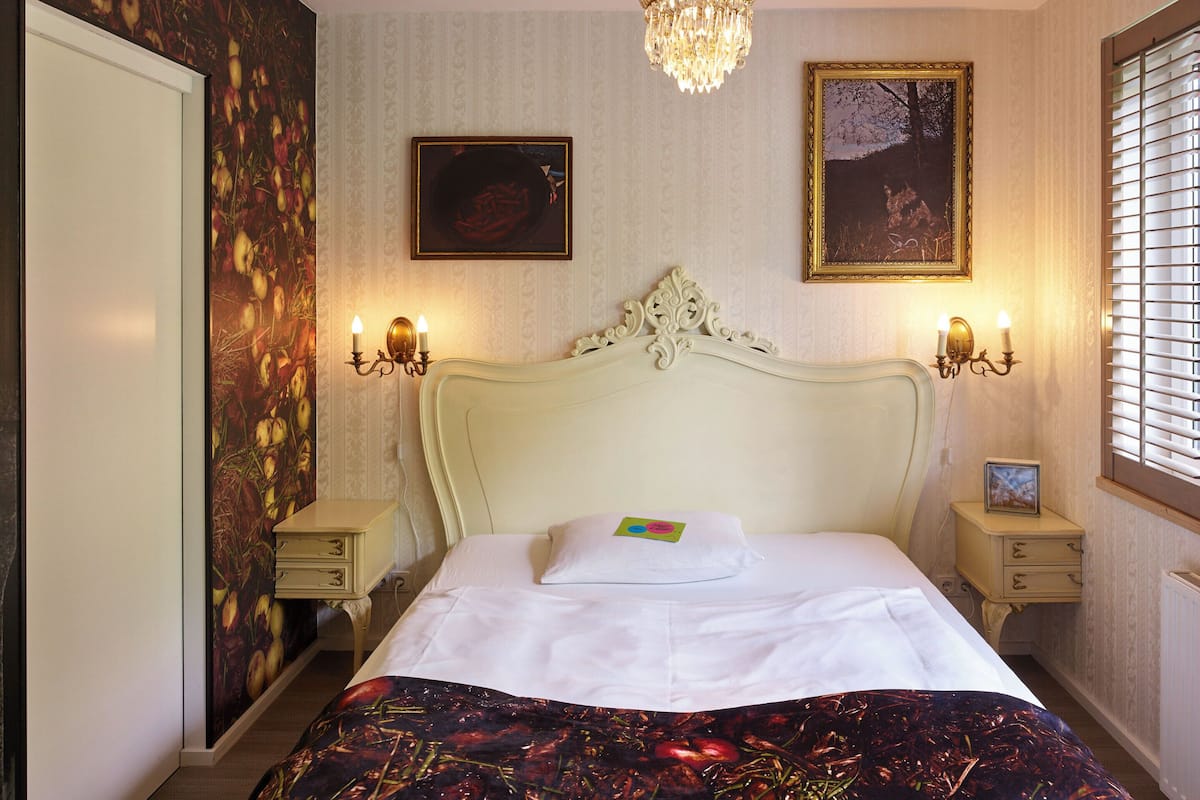 Una cama bien hecha con una colcha de estampado floral, una araña y dos lámparas de pared.